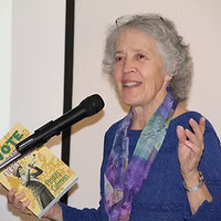 Penny Colman holding her book The Vote: Women's Fierce Fight during a presentation.